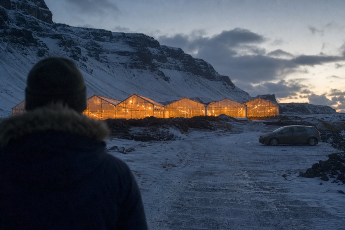 Friðheimar greenhouses glowing orange at dusk under snow in the Reykholt valley