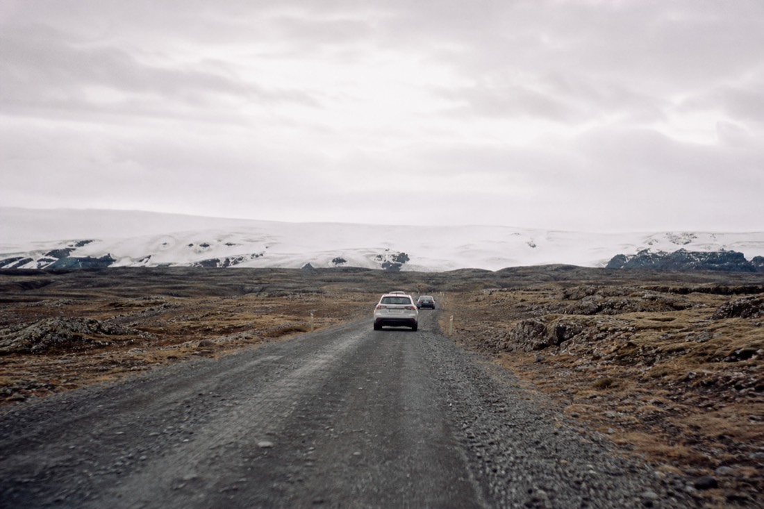 Open gravel highland road running toward the Langjökull glacier under a wide grey sky