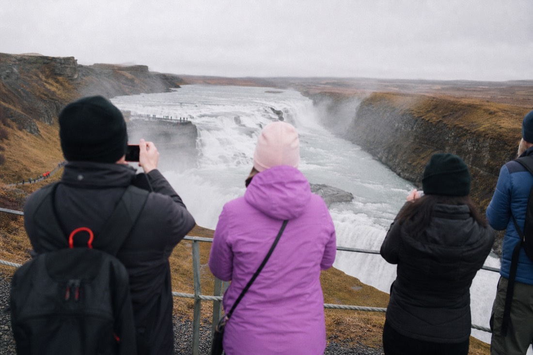 Visitors lingering along the upper viewing platform at Gullfoss with the gorge below