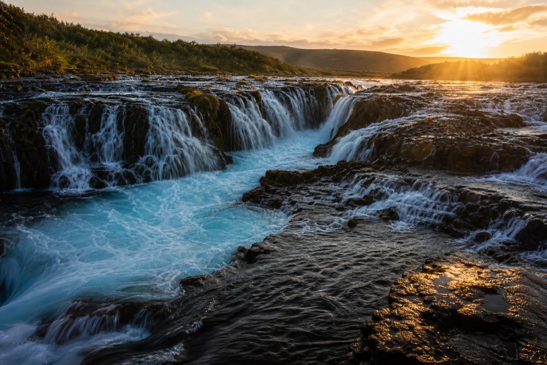 The blue cascades of Brúarfoss waterfall in low golden evening light with no other visitors