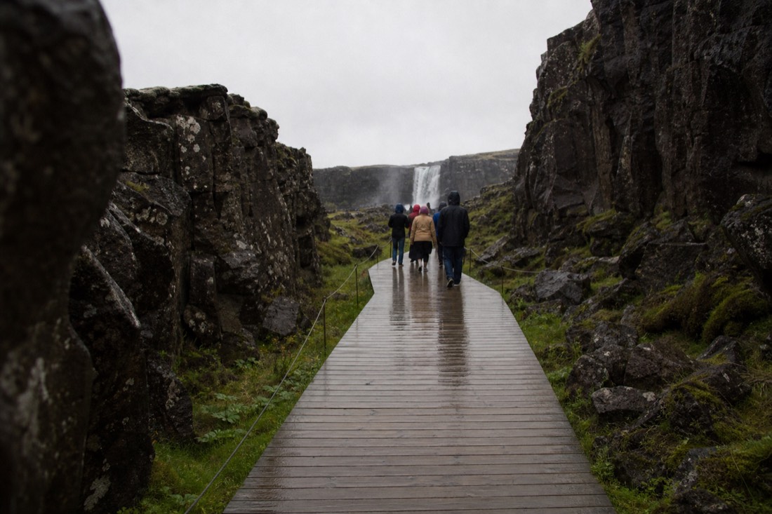 Wet boardwalk leading to Öxarárfoss inside the Almannagjá gorge in light drizzle