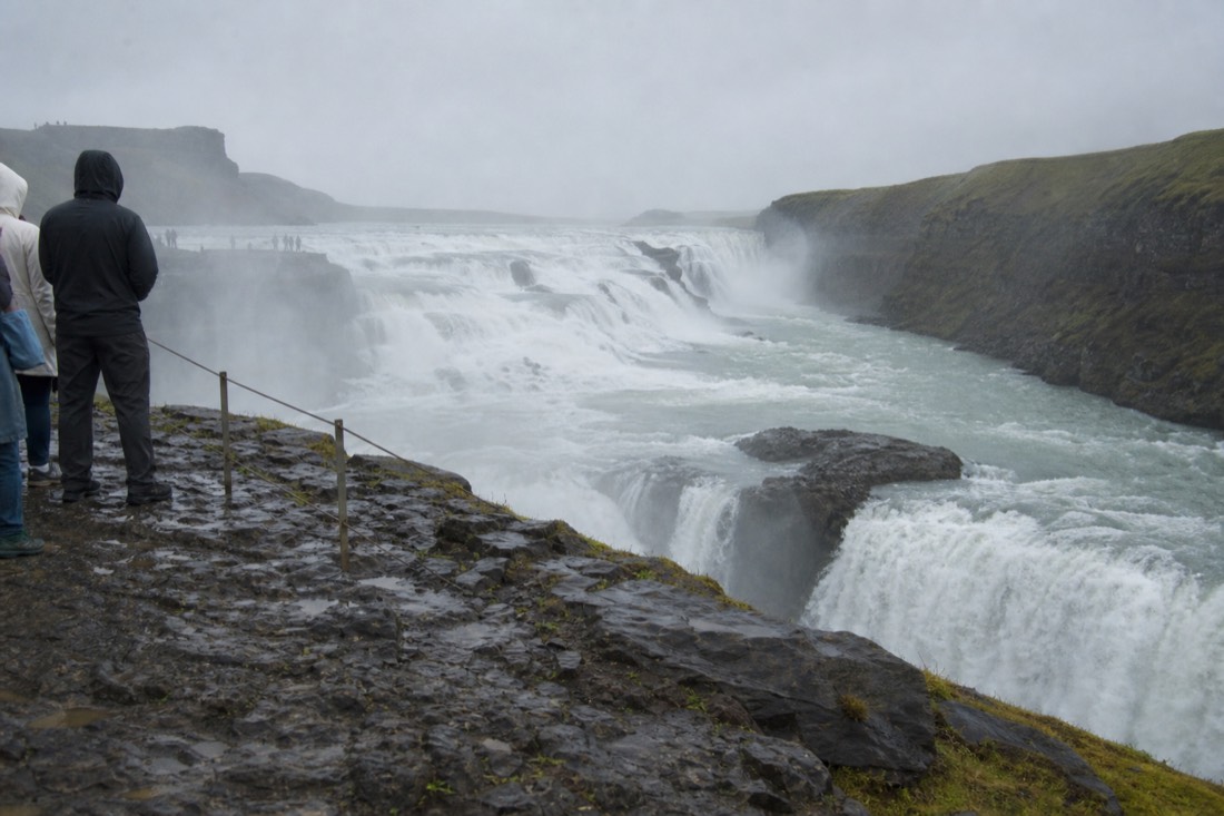 Gullfoss waterfall thundering into its canyon under grey drizzle with spray hanging in the air