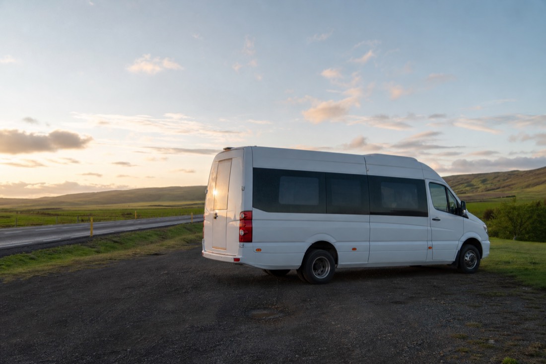 Unbranded tour minibus parked beside route 35 near Faxi in low golden evening light