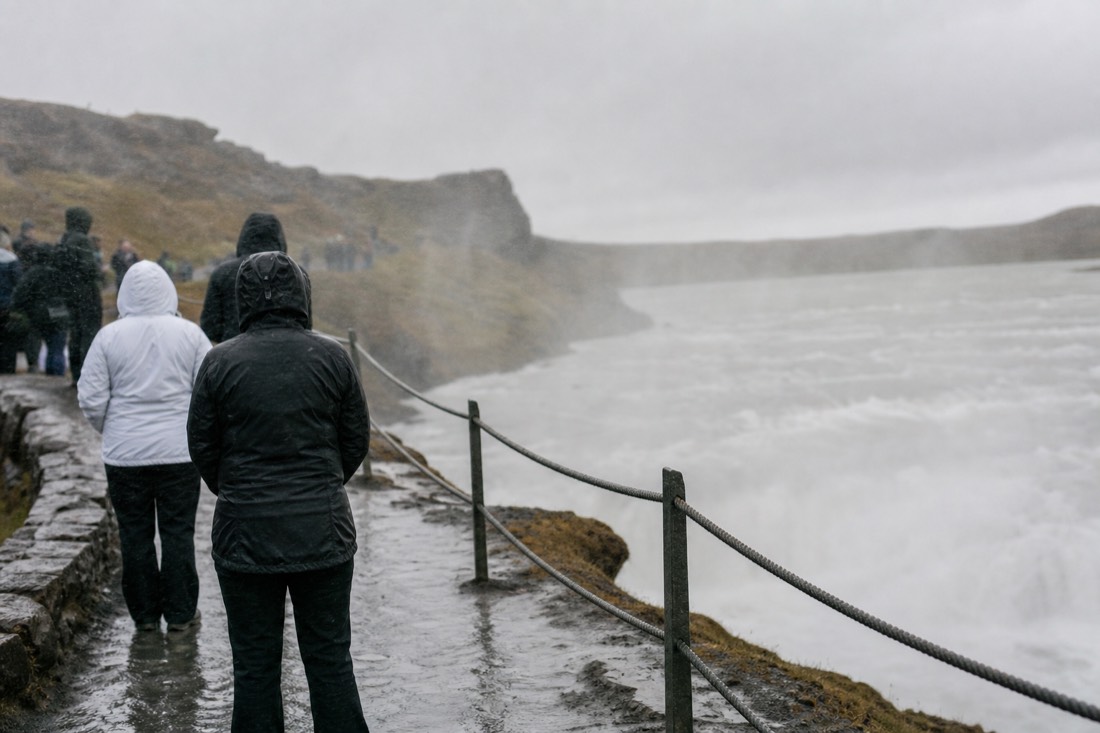 Sideways spray drifting over the wet rope railing at the Gullfoss viewing platform in drizzle
